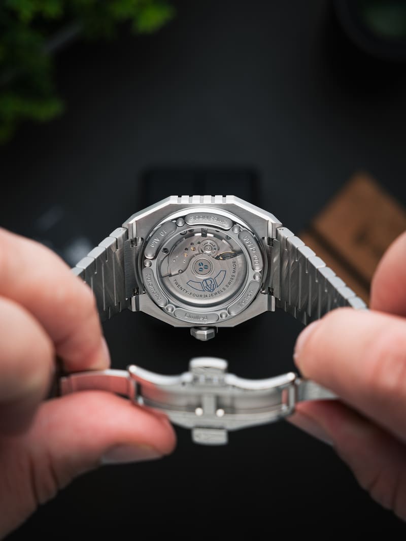 DWISS A1 luxury Swiss automatic wristwatch during hands-on review, showcasing the sapphire exhibition caseback, mechanical movement, and stainless steel construction.